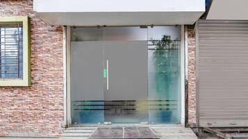A building entrance with a glass door, a metal ramp, and a brick wall.