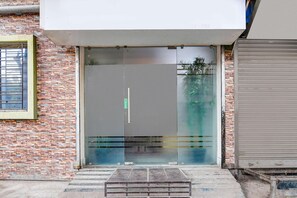A building entrance with a glass door, a metal ramp, and a brick wall. - Classic With Balcony Skyline Serenity (Bidhannagar)