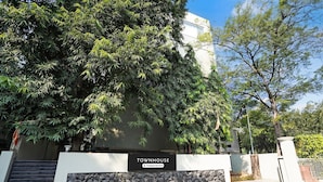 A sign for 'TOWNHOUSE' with a stone wall and a gate, surrounded by trees. - Super Deluxe Octave Parkland Suites (Nagpur)