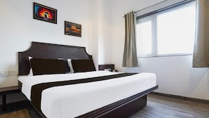 A hotel room with a large bed, a window with curtains, and two framed pictures on the wall. - Super Deluxe Octave Parkland Suites (Nagpur)