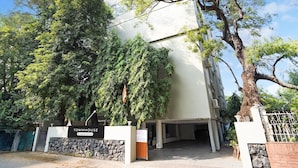 A building labeled 'TOWNHOUSE & Company Service' with a stone wall entrance, large trees, and a clear sky. - Super Deluxe Octave Parkland Suites (Nagpur)