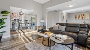 Uma sala de estar moderna com um sofá de couro, uma mesa de centro e um espaço de jantar com cadeiras e uma mesa.