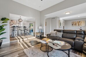 Ein modernes Wohnzimmer mit Ledersofa, Couchtisch und einem Essbereich mit Stühlen und Tisch.