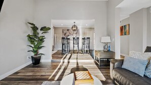 Uma sala de estar moderna com piso de madeira, uma planta grande em vaso, uma mesa de centro e um sofá.