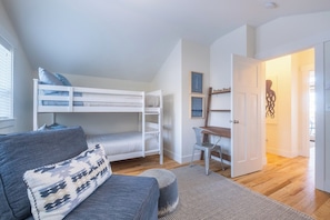 Ett rum med våningssängar, ett skrivbord, en stol och en soffa.