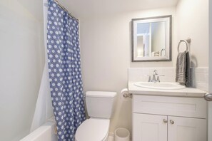 Een badkamer met toilet, wastafel, spiegel en douchegordijn.