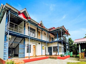 A two-story building with a balcony, a staircase, and a red pathway leading to the entrance. - Classic With Balconymoner Manush (Alipurduar)