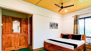Un dormitorio con cama de madera, ventilador de techo, armario de madera y ventana con cortinas.