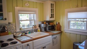 A kitchen with a stove, sink, microwave, and cabinets. - Escape to this charming 1-bedroom Cape cottage, .4 miles to the beach (Dennis Port)