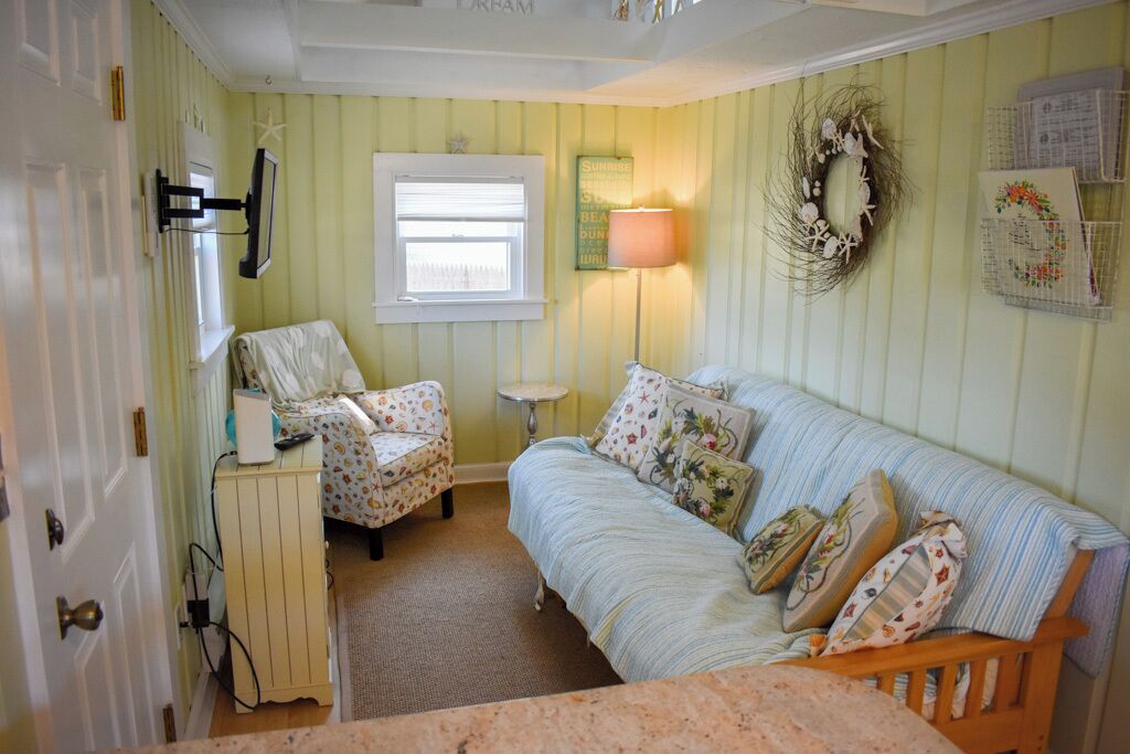 A room with a bed, a chair, a lamp, and a wall-mounted shelf.