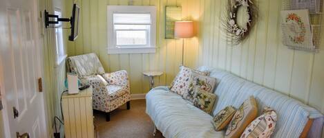 A room with a bed, a chair, a lamp, and a wall-mounted shelf.