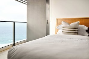 Ein Hotelzimmer mit großem Fenster, einem Bett mit weißer Bettwäsche und einem hölzernen Kopfteil.