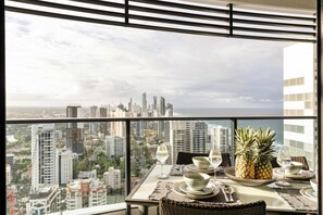 Un comedor con una mesa para dos, vistas a la ciudad y un balcón con barandilla.