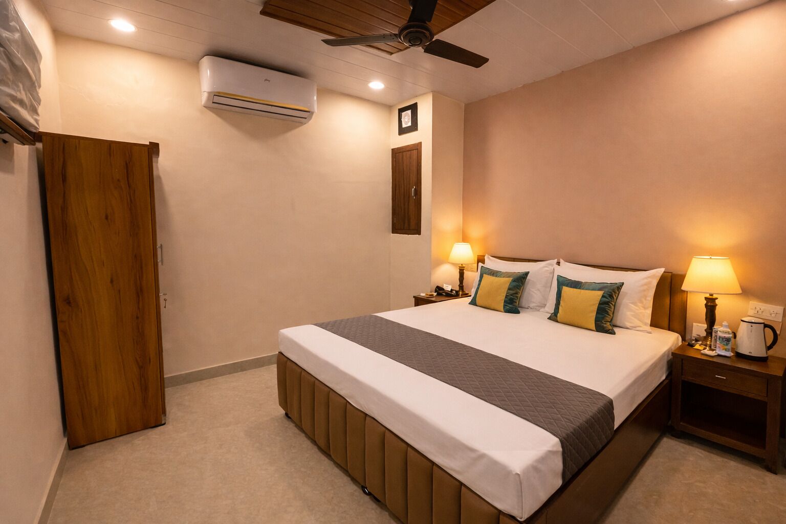 Quarto de hotel com cama, mesas de cabeceira, ar condicionado e ventoinha no teto.
