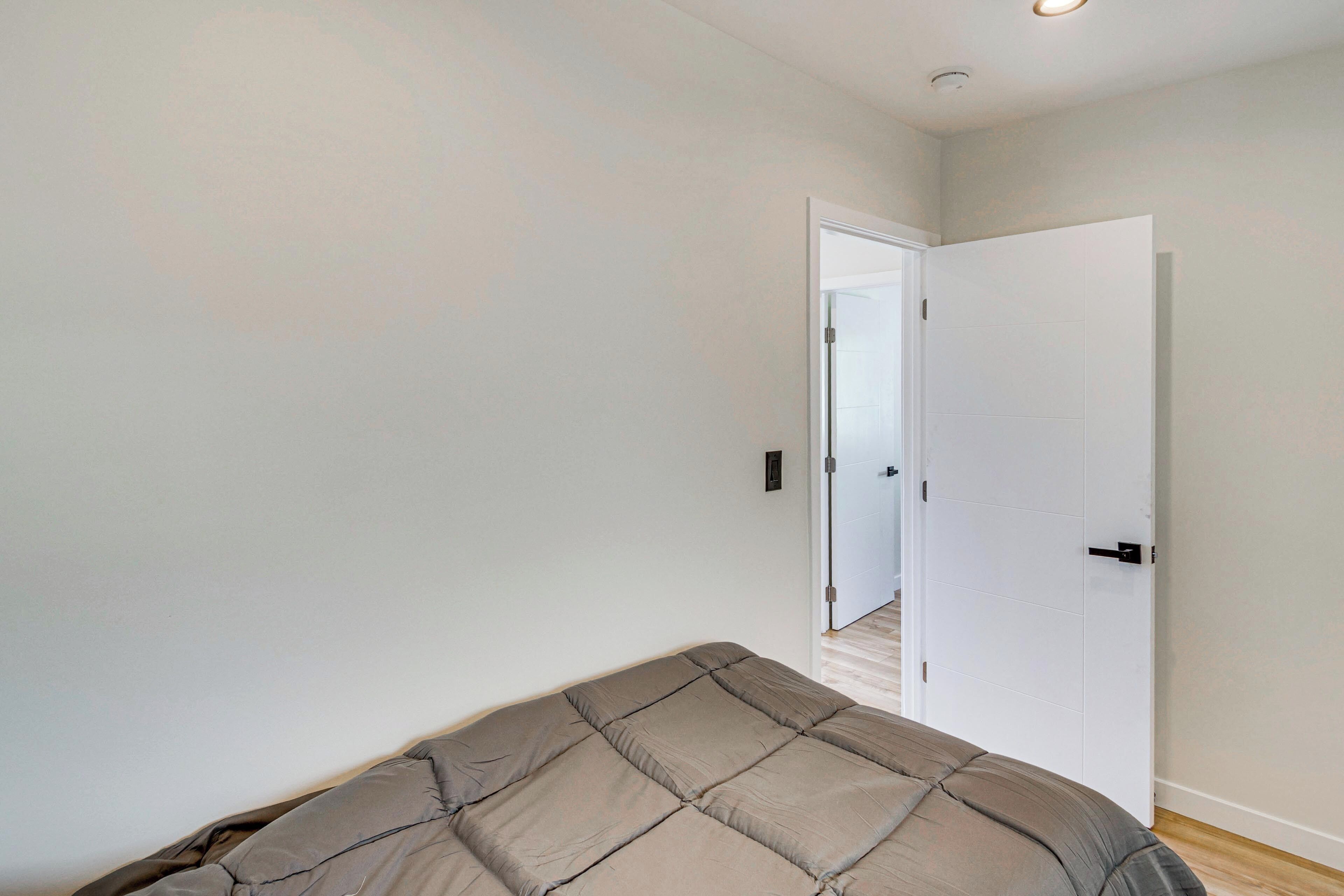 Une chambre à coucher avec un lit, une porte blanche et un couloir menant à une autre pièce.
