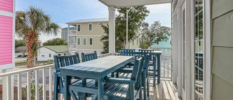A covered outdoor area with a table and chairs, a ceiling fan, and a view of neighboring houses.