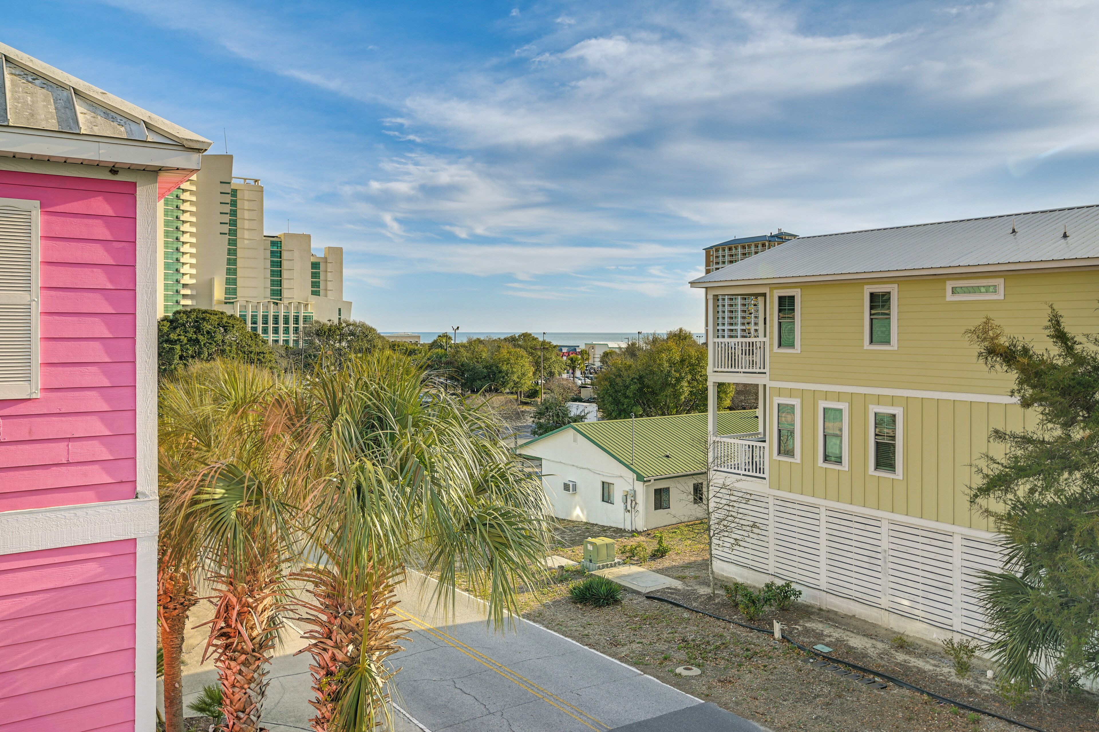 A residential area with a pink house, a yellow house, and a white building with a green roof.