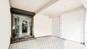 A room with a patterned floor, a glass door entrance, and a plain white wall. - Deluxe Vinayak Residency Patravakam Inn (Chennai)