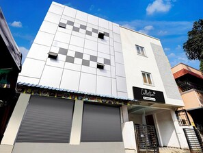 A modern building with a flat roof, a large garage door, and a sign that reads 'Collection Company Services.' - Deluxe Vinayak Residency Patravakam Inn (Chennai)