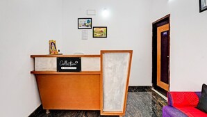 A reception desk with a sign reading 'Collection,' a framed picture on the wall, and a couch with a red cushion. - Deluxe Vinayak Residency Patravakam Inn (Chennai)