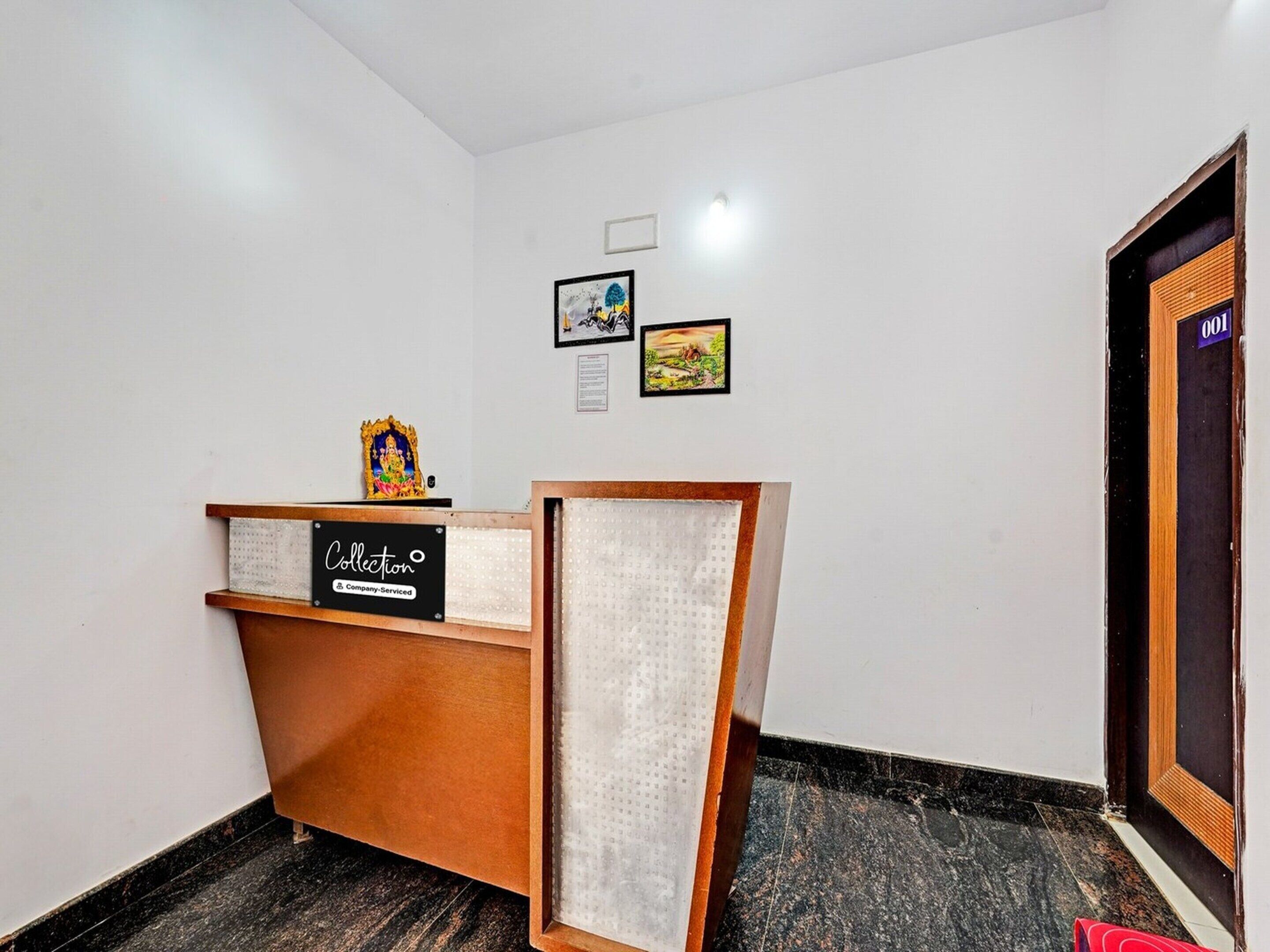 A reception desk with a sign, a small statue, and two framed pictures on the wall.