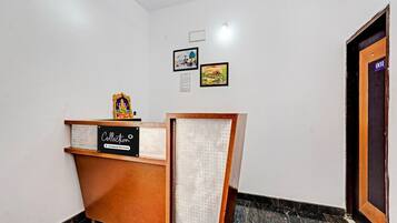 A reception desk with a sign, a small statue, and two framed pictures on the wall.