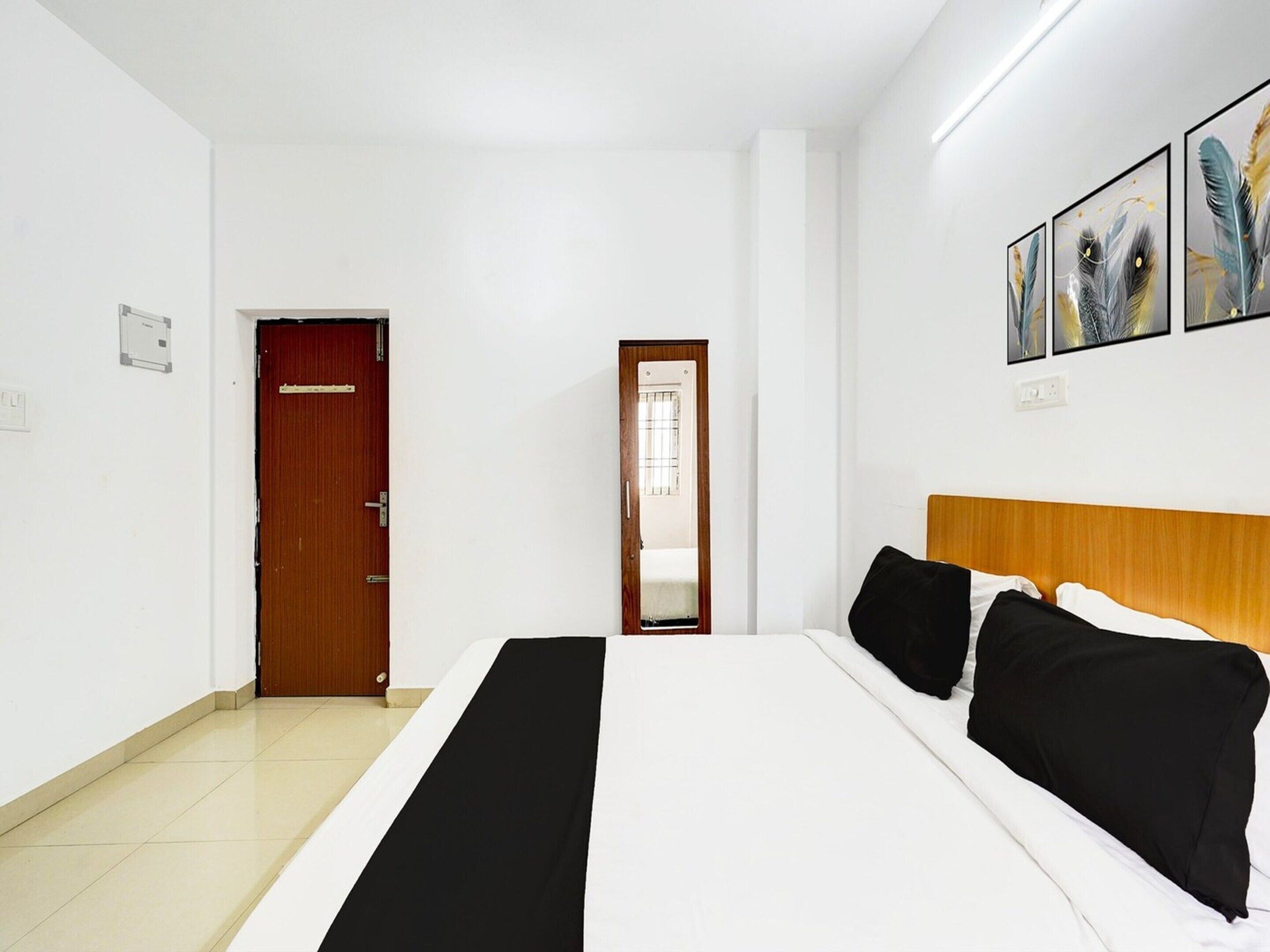 A hotel room with a bed, a wooden headboard, a door, and a wall-mounted artwork.