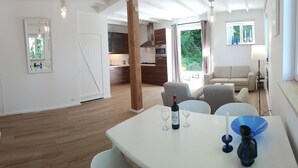A modern kitchen with wooden cabinets, a dining area with a table set for two, and a view of the outdoors. - Le Sommet. Rural setting with beautiful views of the Morvan hills (Préporché)