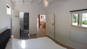 Un dormitorio con una cama, una mesita de noche, una ventana y una puerta que da a un baño.
