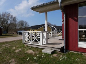 A building with a red exterior, a white porch with a railing, and a clear sky. - 4 Star Holiday Home in Grossenbrode (Grossenbrode)
