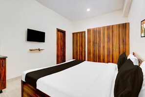 A bedroom with a bed, a TV mounted on the wall, and wooden wardrobes. - Deluxe Collection O Sadar Bazaar (Gurugram)