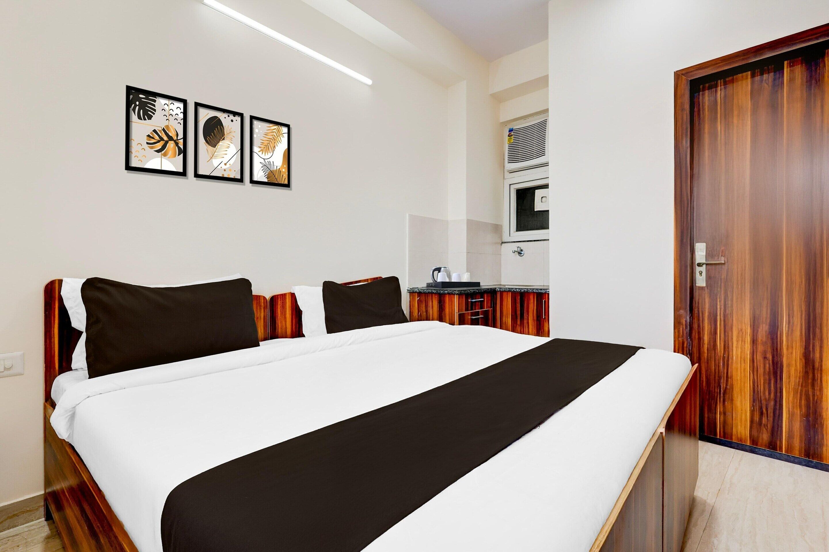 Quarto de hotel com cama, cozinha compacta e porta.