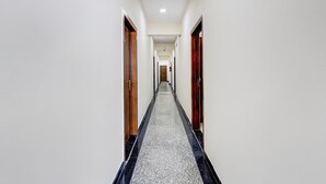 A long, narrow hallway with doors on both sides, a tiled floor, and a ceiling light. - Super Collection O Sadar Bazar Gurgaon (Gurugram)