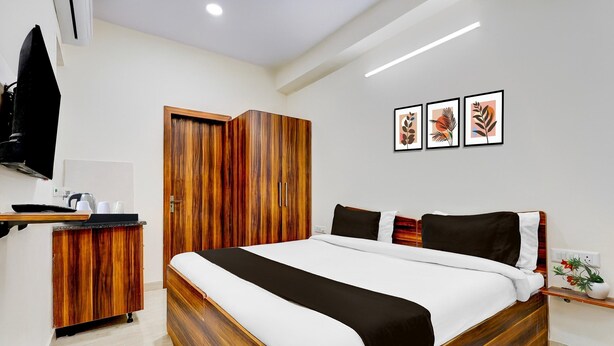 A bedroom with a wooden bed, a wardrobe, a flat-screen TV, and framed artwork on the wall. - Super Collection O Sadar Bazar Gurgaon (Gurugram)