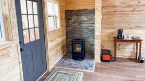 Ein Holzblockhaus-Interieur mit einer schwarzen Tür, einem Kamin, einem Tisch mit einer Kaffeemaschine und einem Heizgerät.