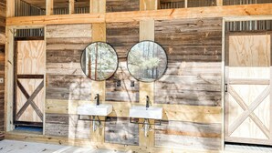 Ein rustikales Badezimmer mit Holzwänden, zwei Waschbecken und zwei runden Spiegeln.