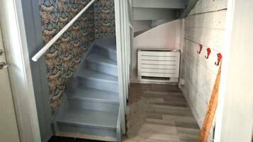 Una escalera con un revestimiento de pared estampado, barandilla y un radiador blanco.