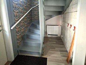 Una escalera con un revestimiento de pared estampado, barandilla y un radiador blanco.
