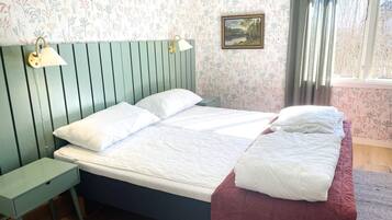 Un dormitorio con una cama, una mesita de noche, una lámpara, un cuadro y una ventana.