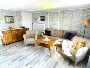 A living room with a sofa, armchairs, a wooden coffee table, a wooden cabinet, and a radiator. - 5 Person Holiday Home in Myresjo (Myresjö)