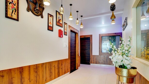 A hallway with wooden paneling, framed artwork, hanging pendant lights, and a potted plant.