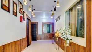 A hallway with wooden paneling, hanging pendant lights, framed artwork, and potted plants.