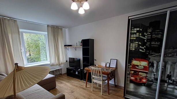 Ein modernes Wohnzimmer mit einer Couch, einem Esstisch, einem Fernseher und einem Bücherregal.