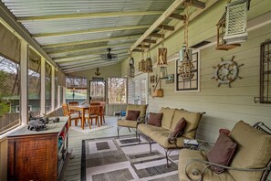 A covered porch with a wooden table and chairs, a sofa, and hanging lanterns. - Drop A Line – Riverfront Relaxation on Little Riverer (Mentone)