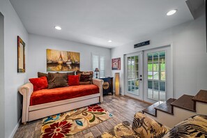 A living room with a sofa, a rug, and a painting on the wall.