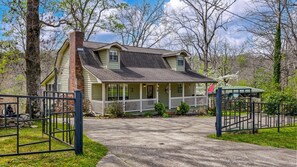 A two-story house with a porch, a brick chimney, and a front gate.