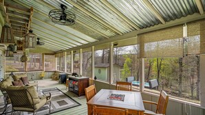A covered porch with a dining table, chairs, a sofa, and a television. - Drop A Line – Riverfront Relaxation on Little Riverer (Mentone)
