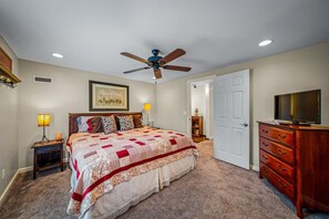 A bedroom with a bed, a ceiling fan, a dresser, a television, and a door leading to another room. - Drop A Line – Riverfront Relaxation on Little Riverer (Mentone)