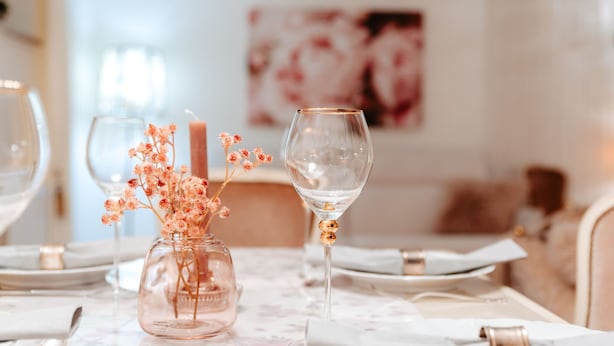 A dining table with a vase of flowers, a candle, and a wine glass. - Apartment Glückliche Zeit 100sqm in the basement with billiard room & garden with terrace (Osterode am Harz)