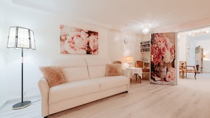 A modern living room with a sofa, a floor lamp, and a large floral painting on the wall. - Apartment Glückliche Zeit 100sqm in the basement with billiard room & garden with terrace (Osterode am Harz)